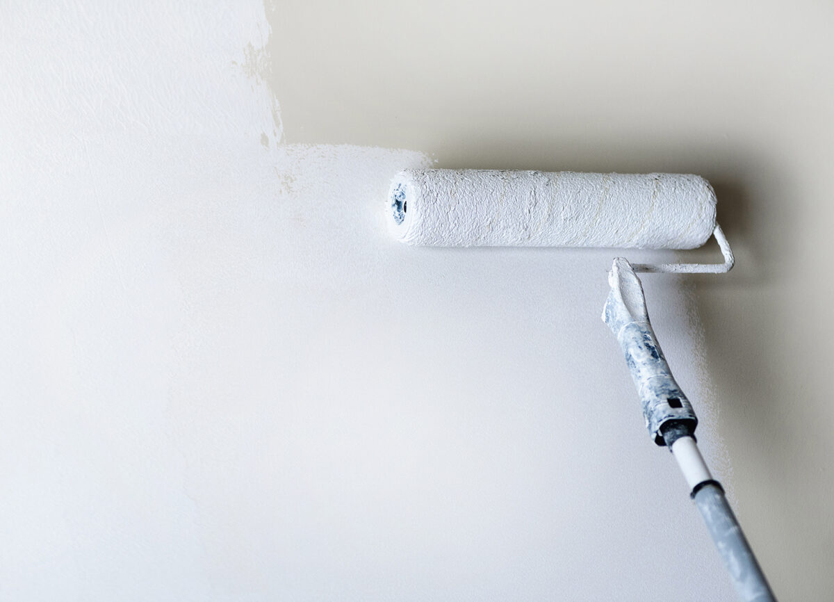 Hand painting wall with paint roller, pastel color. Appartment renovation, repair, building and home concept. Copy space, banner. Tools for painting walls.